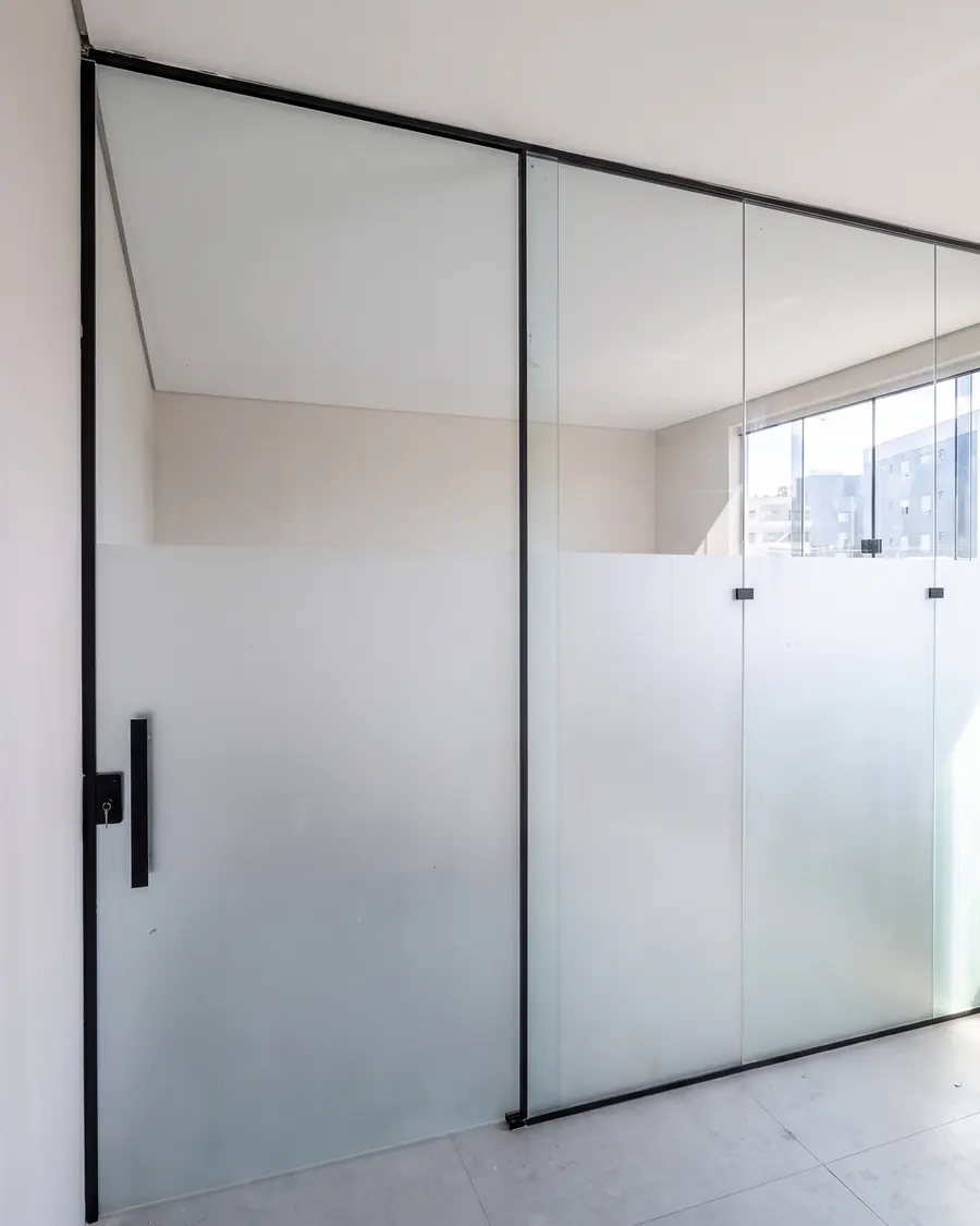 Divisória de vidro temperado com faixa jateada e porta de abrir, com esquadria preta