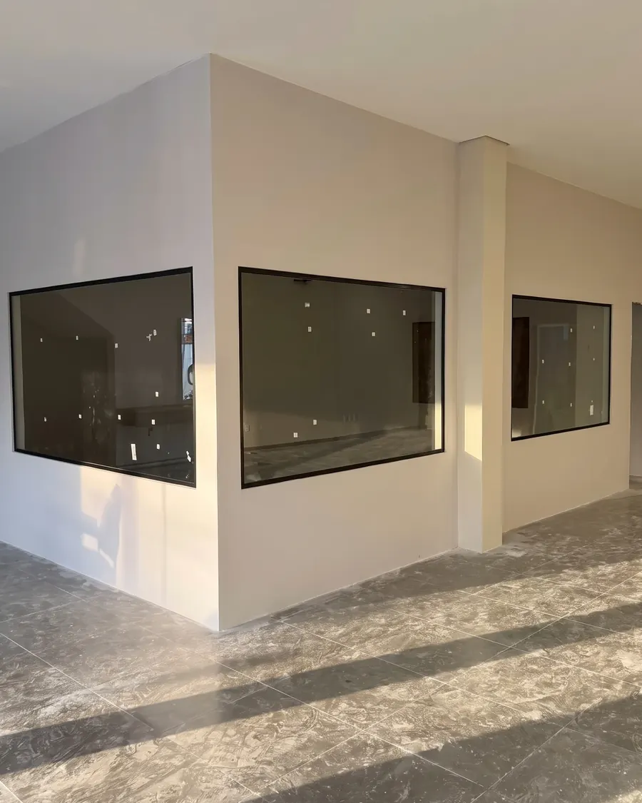 Três janelas fixas em vidro escuro numa obra em acabamento
