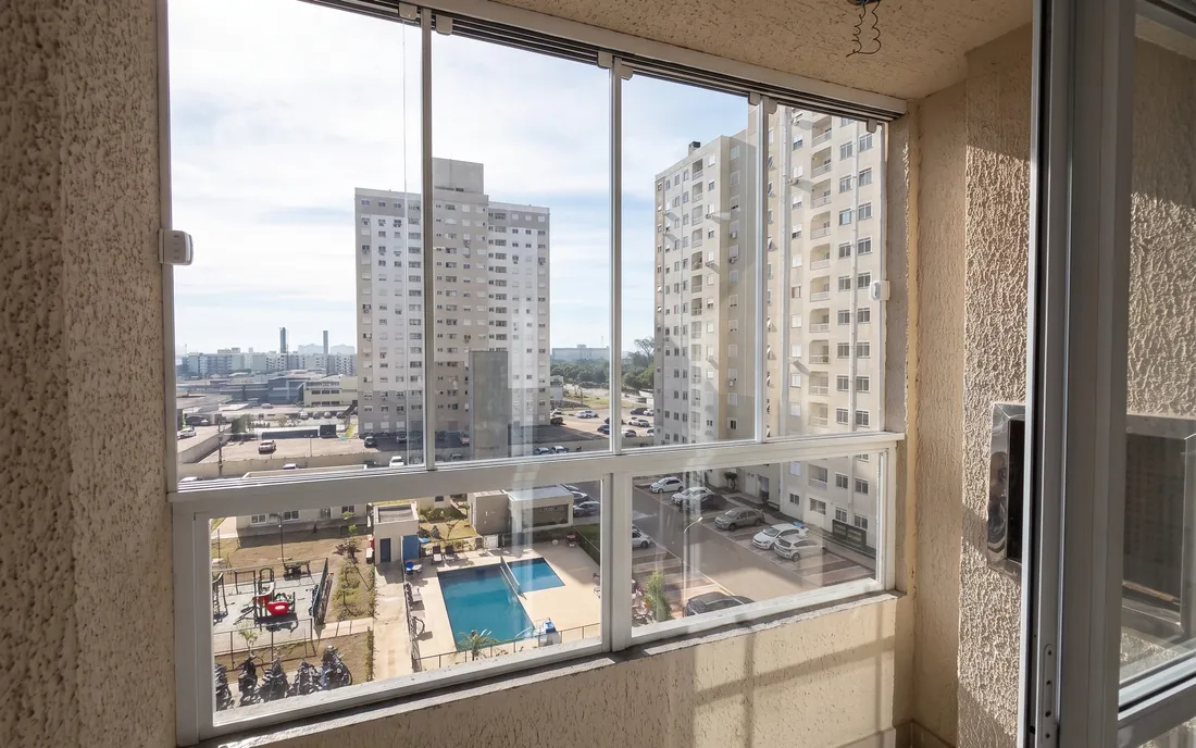 Sacada envidraçada com vista para o pátio do condomínio